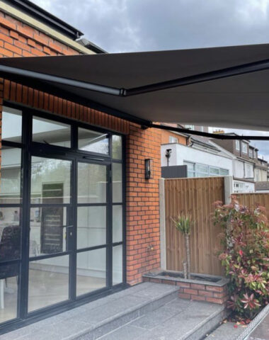 Dark grey awning covering a large glass door.