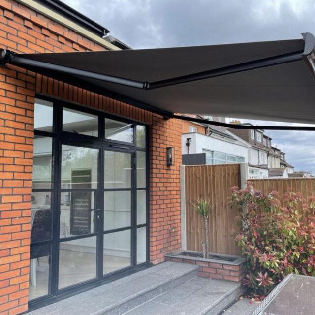 Dark grey awning covering a large glass door.