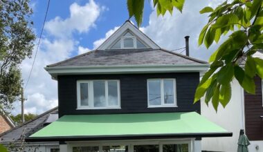 Green awning covering a white brick patio.