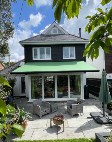 Green awning covering a white brick patio.