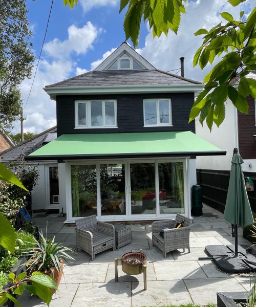 Green awning covering a white brick patio.