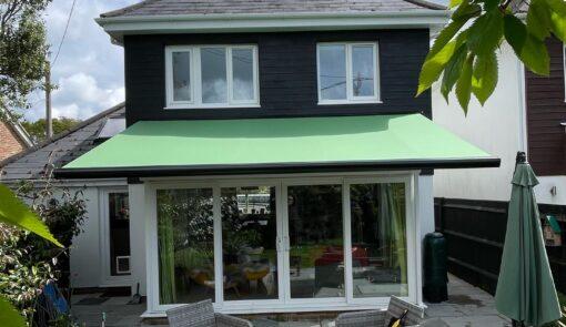 Green awning covering a white brick patio. - Cyra Group Ltd