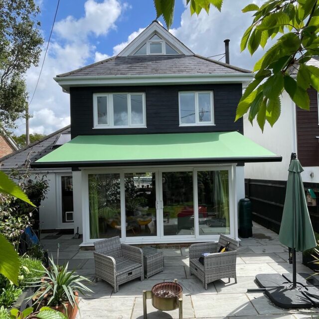 Green awning covering a white brick patio.
